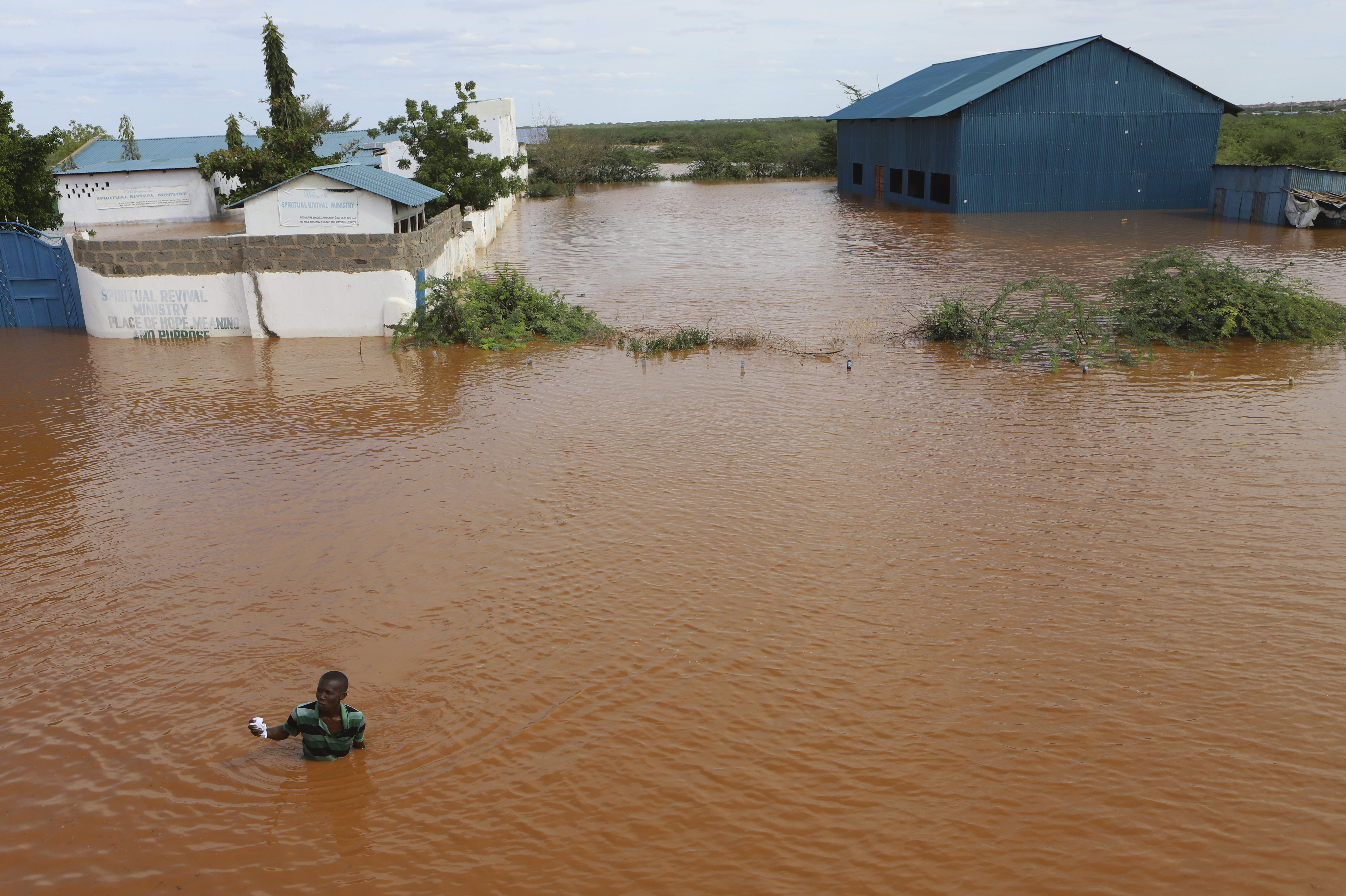 A man swims from a submerged church compound, after the River Tana broke its banks following heavy rains at Mororo, border of Tana River and Garissa counties, northeastern Kenya, April 28. Heavy rains pounding different parts of Kenya have led to dozens of deaths and the displacement of tens of thousands of people, according to the United Nations.