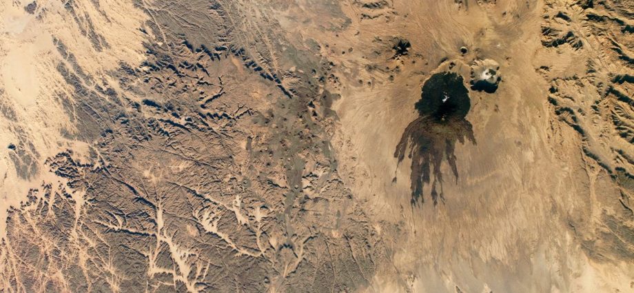 Shadowy tendrils of ancient lava have scarred a dark volcano next to a ‘skull’ in the Sahara — Earth from space